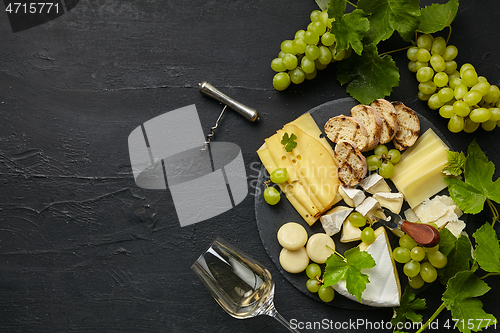 Image of Top view of tasty cheese plate with fruit on the black stone