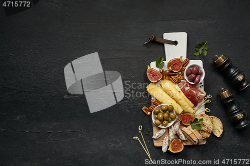 Image of Top view of tasty cheese plate with the fruit on the black stone