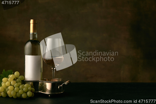 Image of Front view of tasty fruit plate with the wine bottle on dark studio background