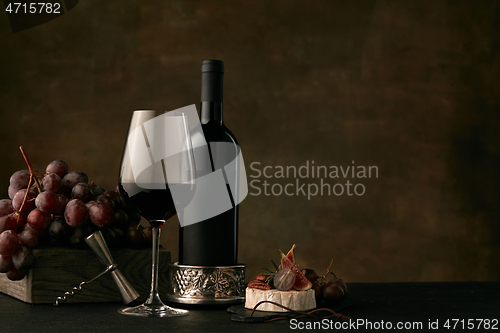 Image of Front view of tasty fruit plate with the wine bottle on dark studio background