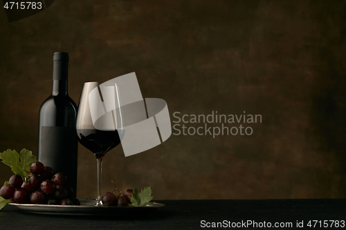 Image of Front view of tasty fruit plate with the wine bottle on dark studio background