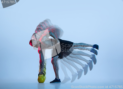 Image of Young caucasian bodybuilder training over blue background