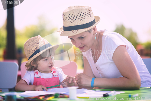 Image of mom and little daughter drawing a colorful pictures