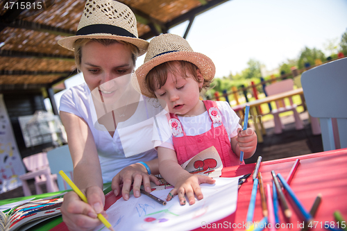 Image of mom and little daughter drawing a colorful pictures