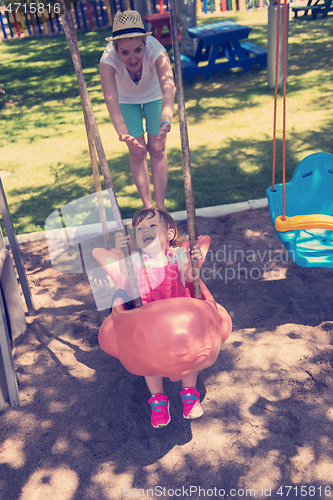 Image of mother and daughter swinging in the park