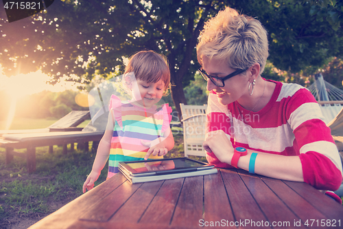Image of mom and her little daughter using tablet computer