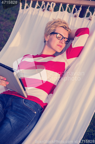 Image of woman using a tablet computer while relaxing on hammock