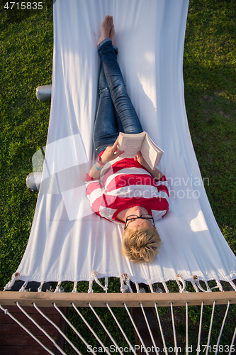 Image of woman reading a book while relaxing on hammock