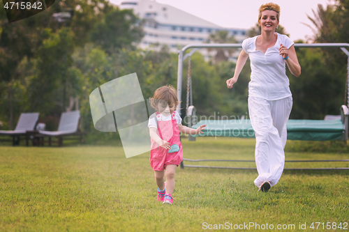 Image of mother and little daughter playing at backyard