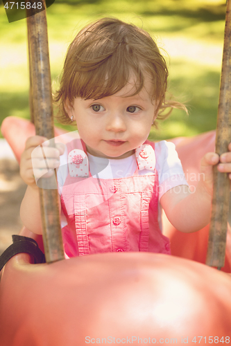 Image of little girl swinging  on a playground