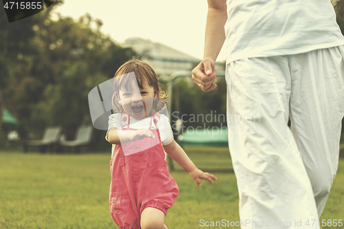 Image of mother and little daughter playing at backyard