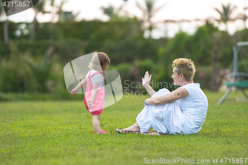 Image of mother and little daughter playing at backyard