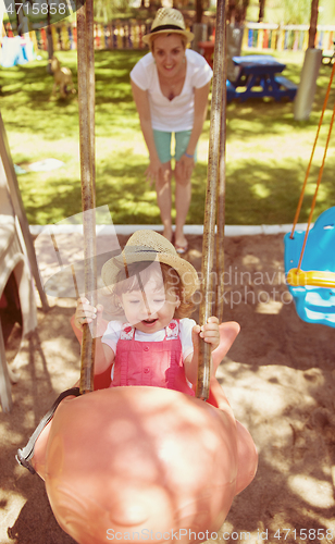 Image of mother and daughter swinging in the park