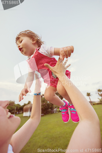 Image of mother and little daughter playing at backyard