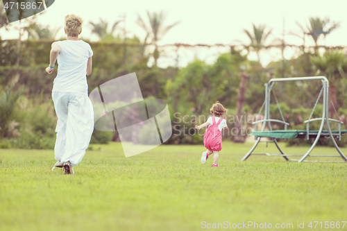 Image of mother and little daughter playing at backyard