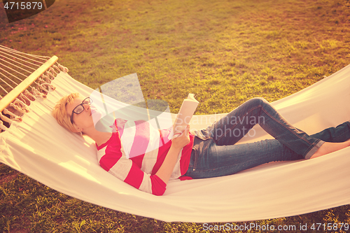 Image of woman reading a book while relaxing on hammock