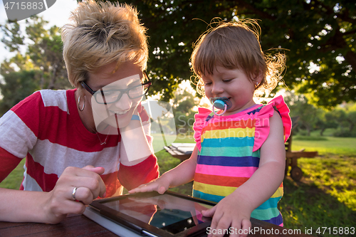 Image of mom and her little daughter using tablet computer