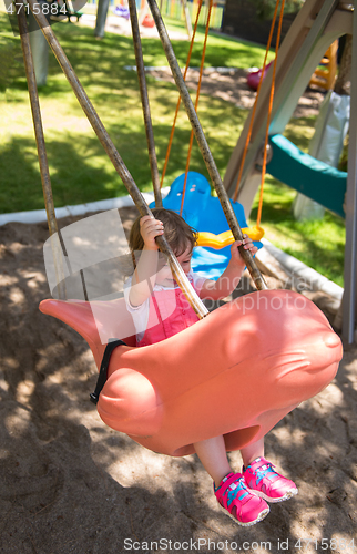 Image of little girl swinging  on a playground