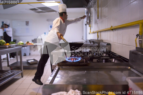 Image of chef preparing food, frying in wok pan