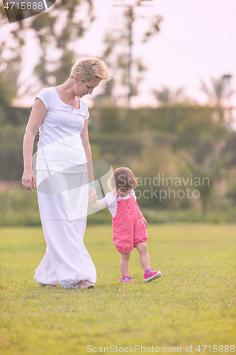 Image of mother and little daughter playing at backyard