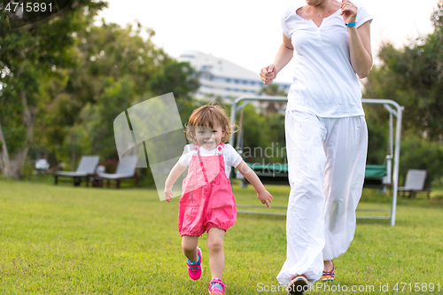 Image of mother and little daughter playing at backyard