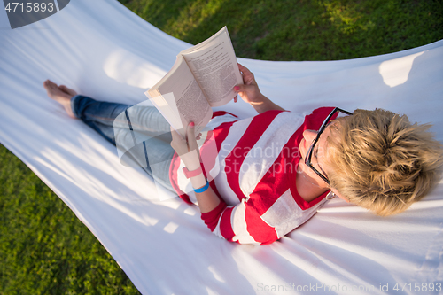 Image of woman reading a book while relaxing on hammock