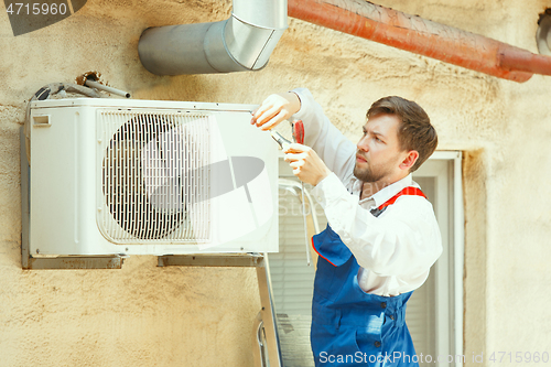 Image of HVAC technician working on a capacitor part for condensing unit