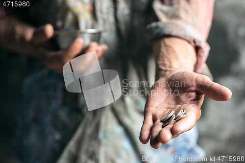 Image of Male beggar hands seeking money on the wooden floor at public path way