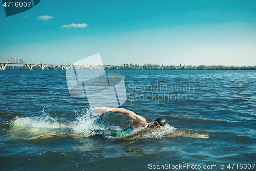 Image of Professional triathlete swimming in river\'s open water