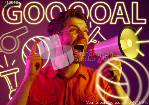 Image of Young man as a football fan isolated on studio background in neon light