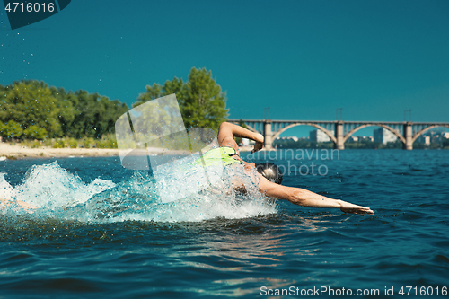 Image of Professional triathlete swimming in river\'s open water