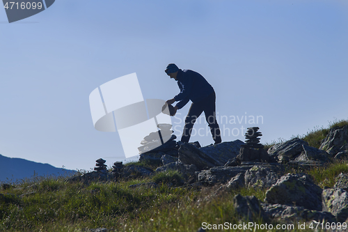 Image of Man silhouette building a stone pile mark