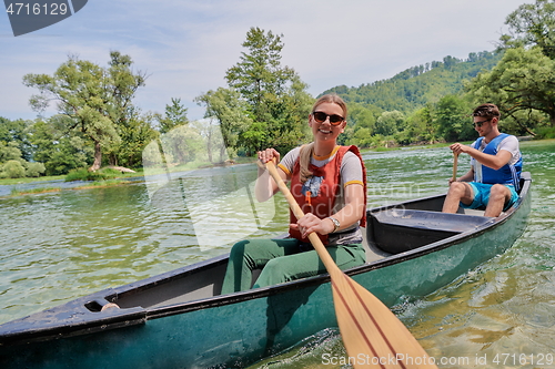 Image of friends are canoeing in a wild river