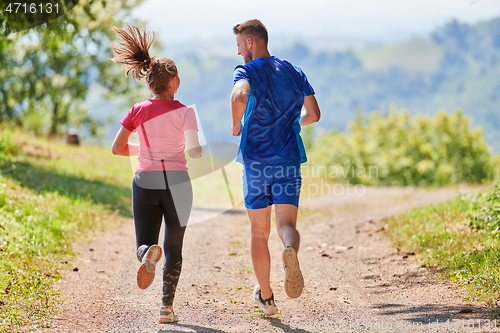 Image of couple enjoying in a healthy lifestyle while jogging on a country road