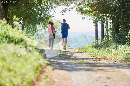 Image of couple enjoying in a healthy lifestyle while jogging on a country road