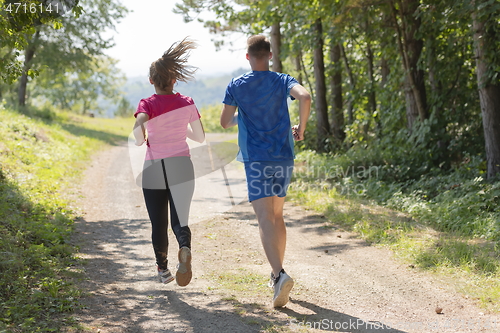 Image of couple enjoying in a healthy lifestyle while jogging on a country road