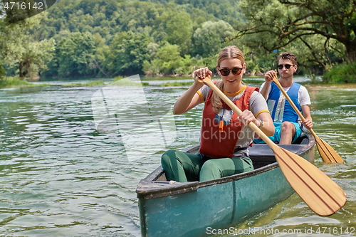 Image of friends are canoeing in a wild river