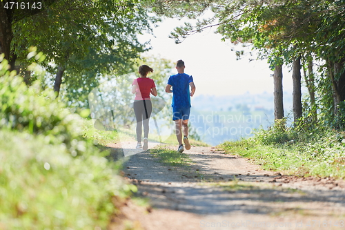 Image of couple enjoying in a healthy lifestyle while jogging on a country road