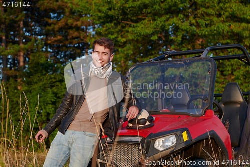 Image of man smoking a cigarette while taking a break from driving a off road buggy car