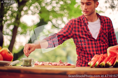 Image of man putting spices on raw meat for barbecue