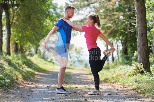 Image of couple enjoying in a healthy lifestyle warming up and stretching before jogging