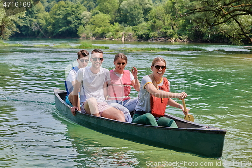 Image of Group adventurous explorer friends are canoeing in a wild river