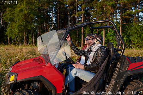 Image of two young happy excited men enjoying beautiful sunny day while driving a off road buggy car