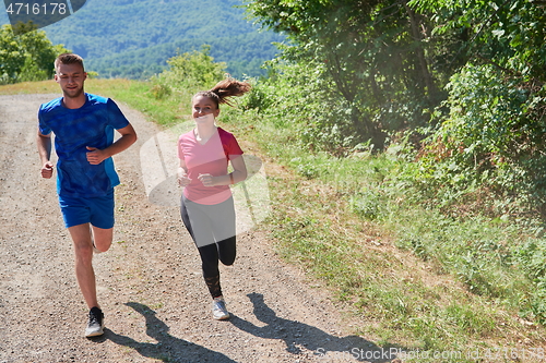 Image of couple enjoying in a healthy lifestyle while jogging on a country road