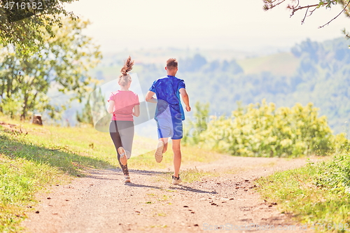 Image of couple enjoying in a healthy lifestyle while jogging on a country road