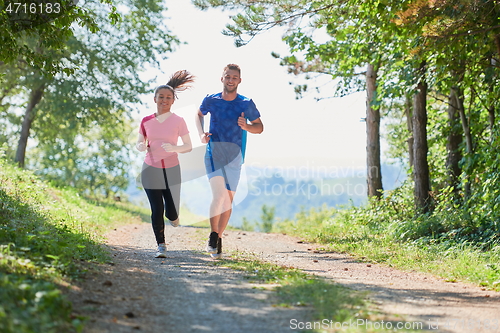 Image of couple enjoying in a healthy lifestyle while jogging on a country road