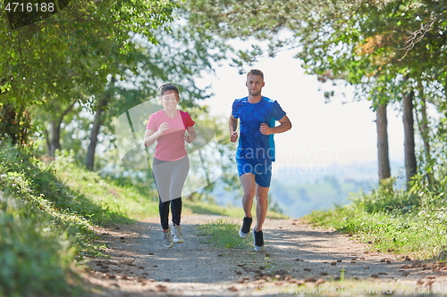 Image of couple enjoying in a healthy lifestyle while jogging on a country road