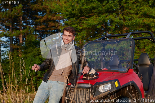 Image of man smoking a cigarette while taking a break from driving a off road buggy car