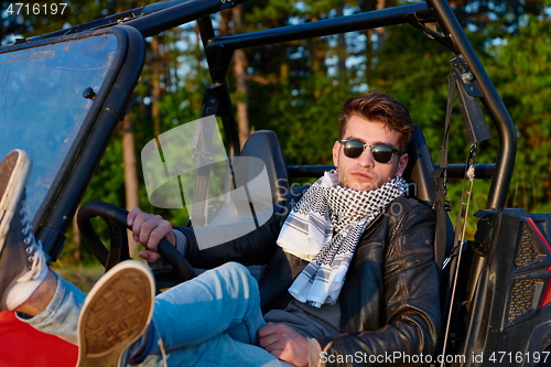 Image of man enjoying beautiful sunny day while driving a off road buggy car