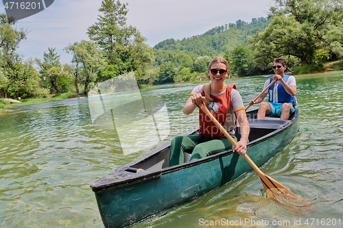 Image of friends are canoeing in a wild river